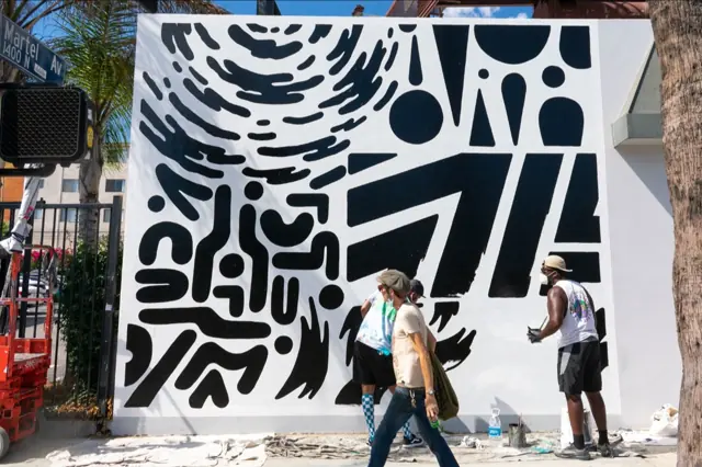 Two painters at work on the black-and-white Upendo wall on Martel Avenue, Los Angeles